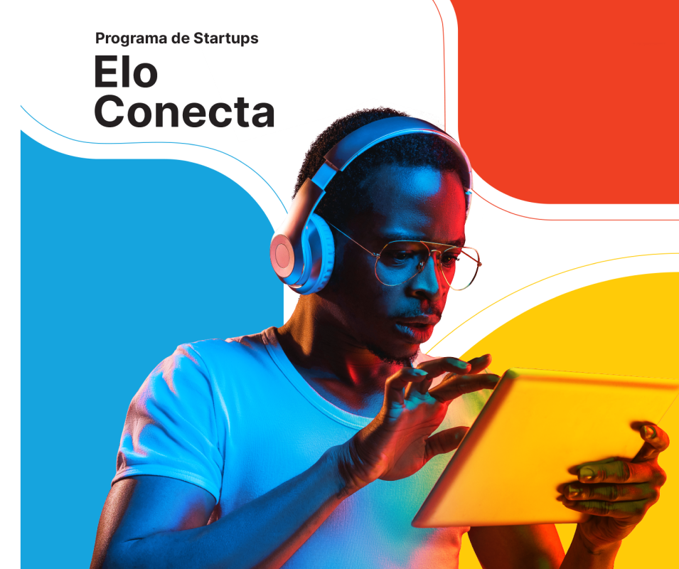 homem de headphones e óculos de grau mexendo em tablet com a escrita programa de startups elo conecta